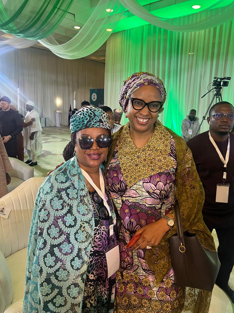 Anna Philemon Dara standing with another woman delegate at a public leadership forum.